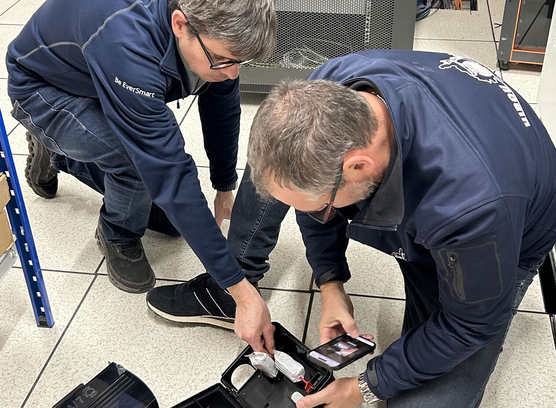 Two technicians installing an EverSmart Pest device on a tiled floor